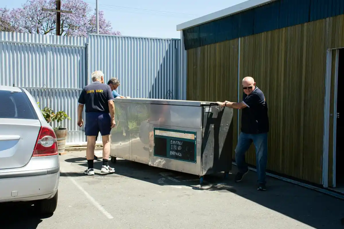 A team of three workers moving a large skip bin into position for installation as part of cheapest skip bins hire launceston tas service